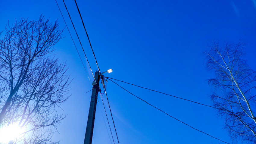 Электроопора с уличным фонарем среди зимних деревьев