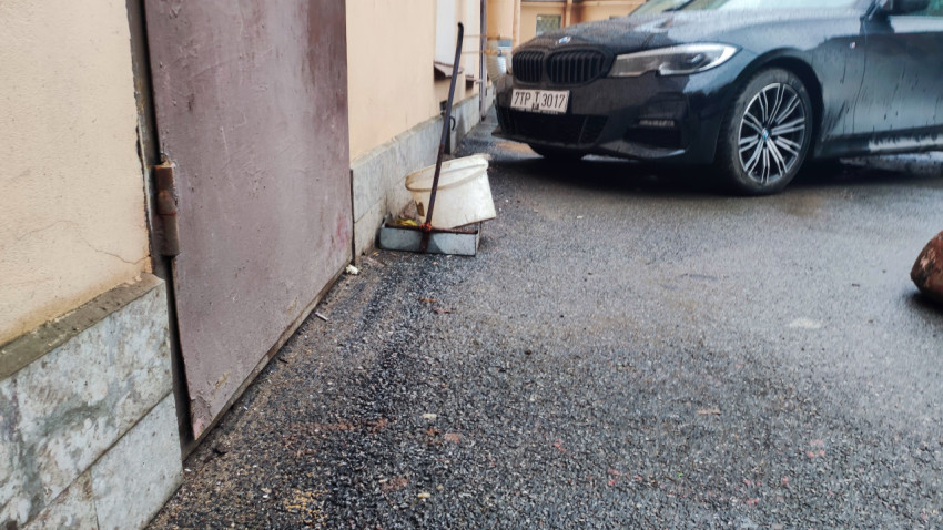 Металлическая дверь во дворе с ведром и машиной