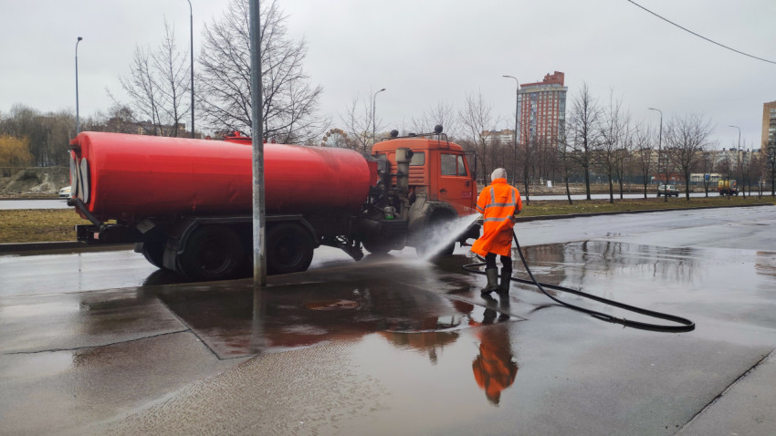 Коммунальный рабочий моет тротуар рядом с цистерной