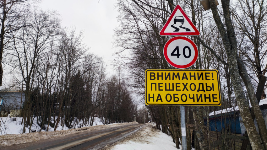 Предупреждающие дорожные знаки на заснеженной загородной дороге