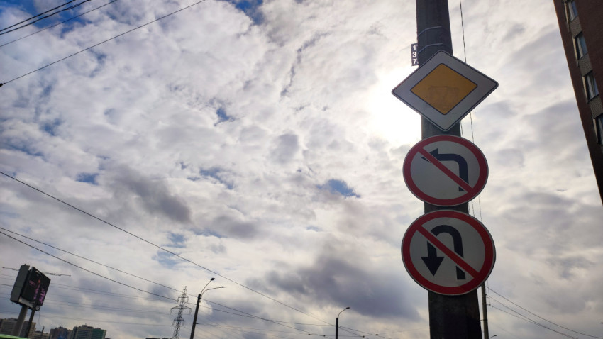 Дорожные знаки «Главная дорога» и запрет поворотов на фоне облачного неба
