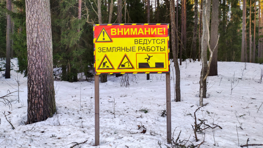 Предупредительный знак о земляных работах в зимнем лесу