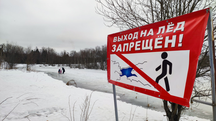 Зимний пейзаж с предупреждающим знаком у замерзшего водоёма