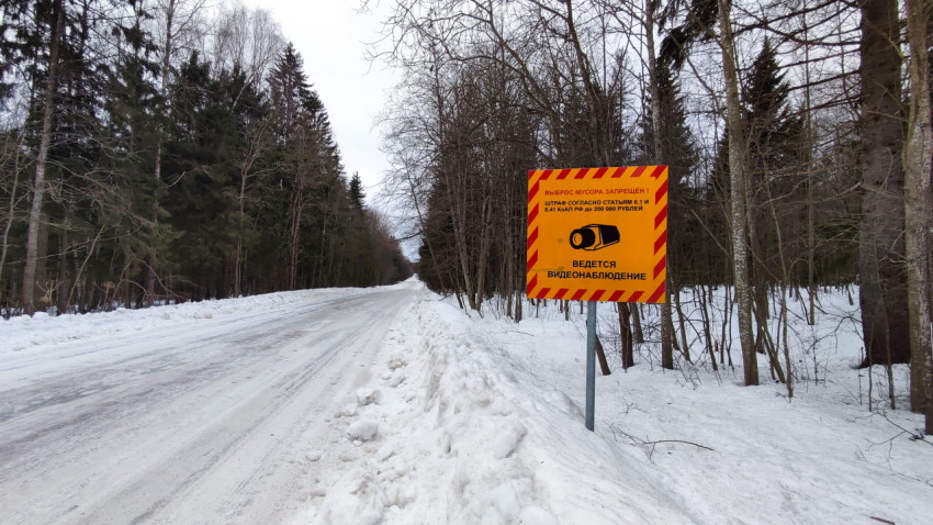 Предупреждающий знак о запрете мусора на зимней дороге через лес