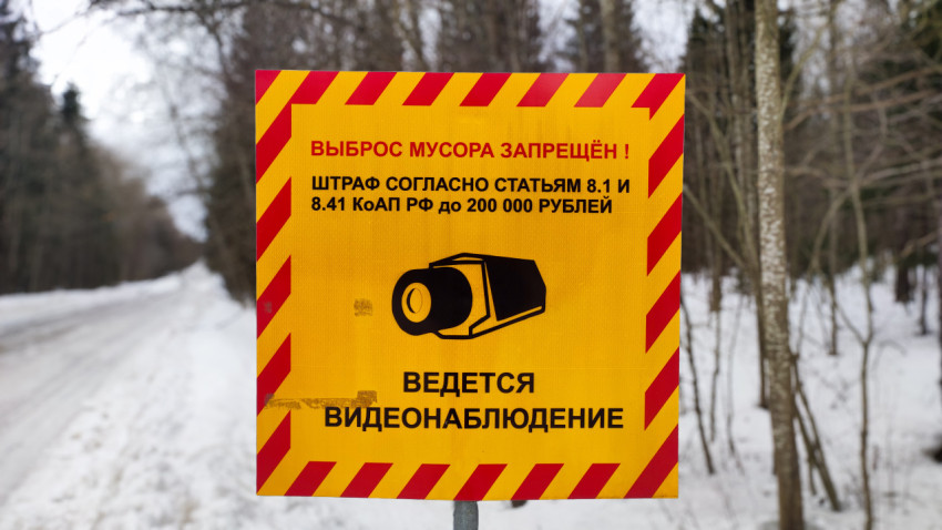 Предупреждающий знак о запрете мусора крупным планом на фоне зимнего леса