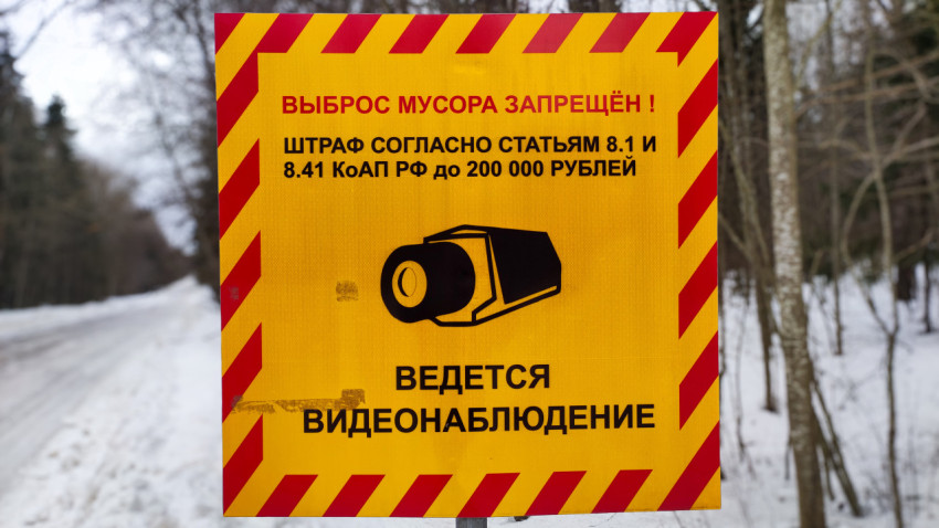 Предупреждающий знак «Выброс мусора запрещён!» крупным планом на фоне леса