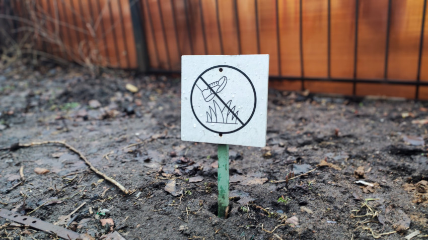 Табличка «По газонам не ходить» на земле у забора