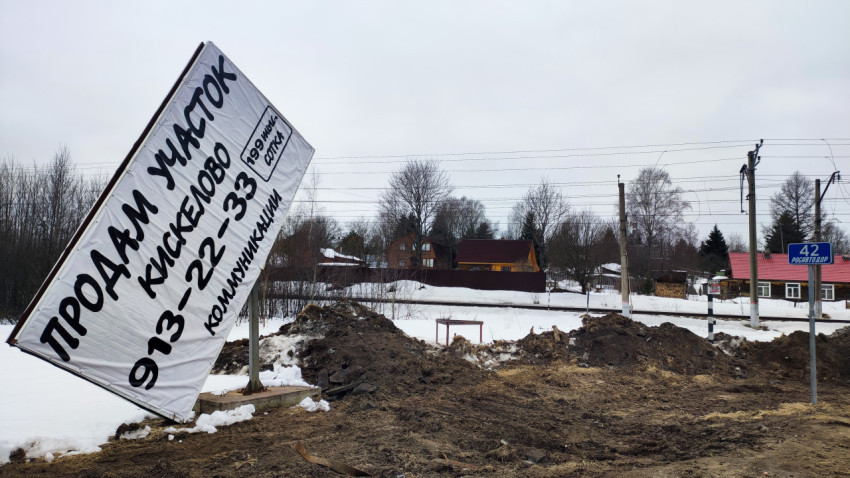 Сломанный рекламный щит на фоне загородных домов зимой