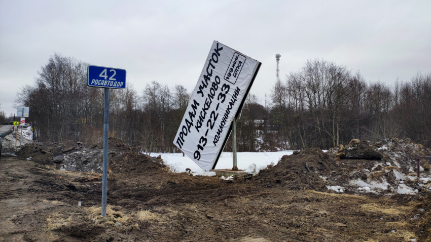 Наклонённый рекламный щит и знак «Росавтодор 42» зимой