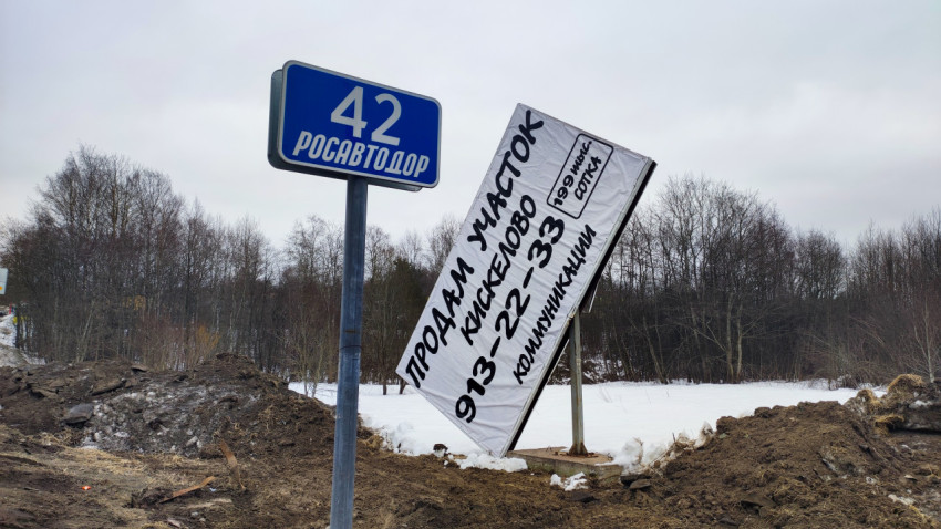 Рекламный щит о продаже земли у трассы с указателем Росавтодора
