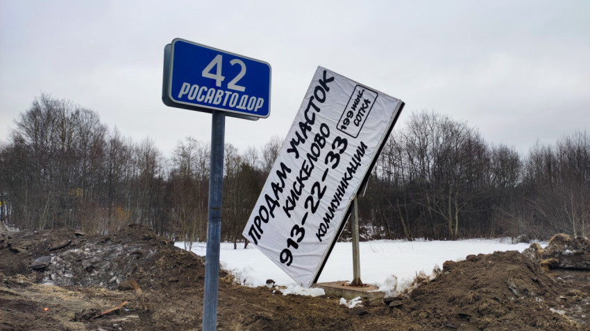 Дорожный указатель «42 Росавтодор» и рекламный баннер на зимней обочине