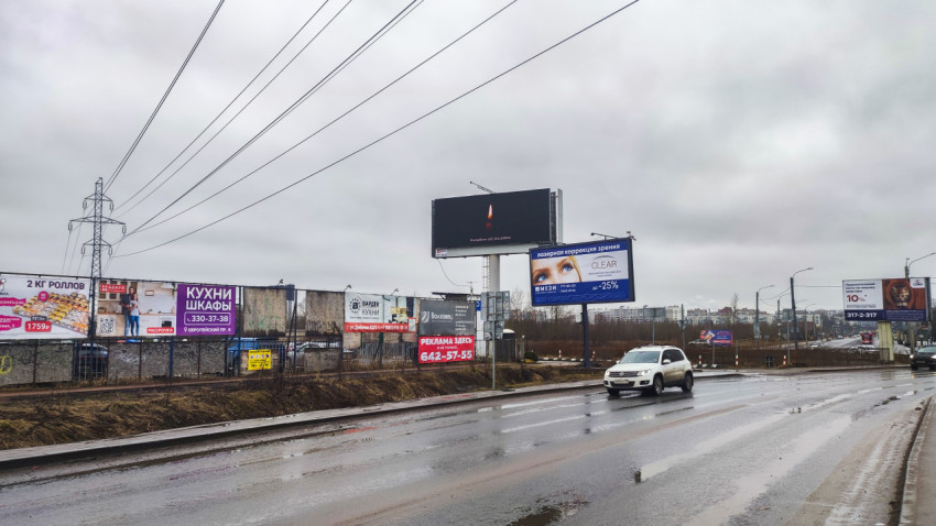 Городская улица с рекламными щитами и проезжающими автомобилями