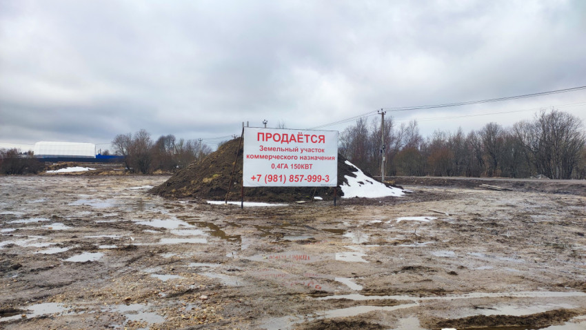 Земельный участок с баннером о продаже на фоне пасмурного неба