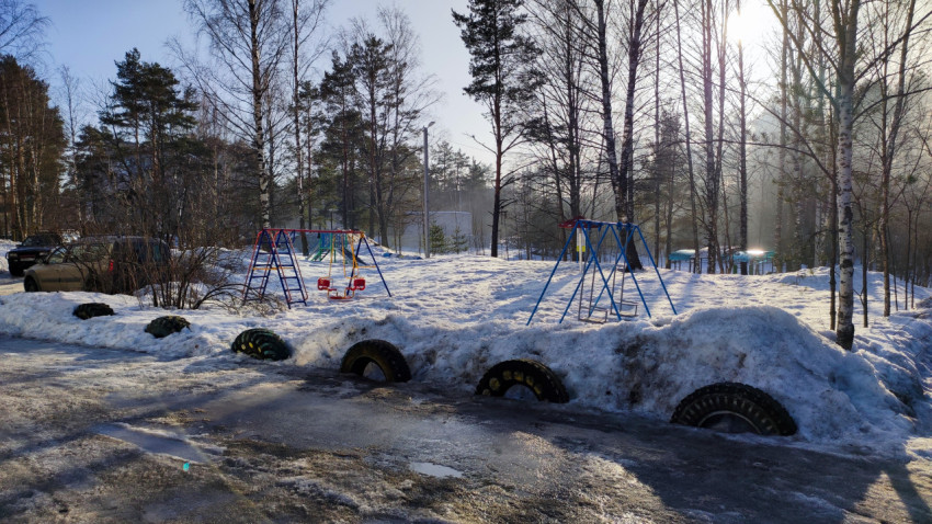 Детская площадка в зимнем парке с качелями