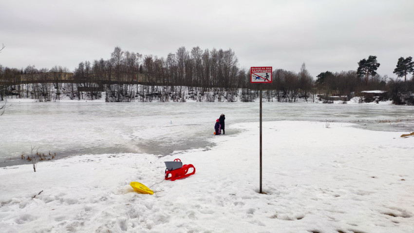 Знак о запрете выхода на лёд и люди на замерзшем пруду
