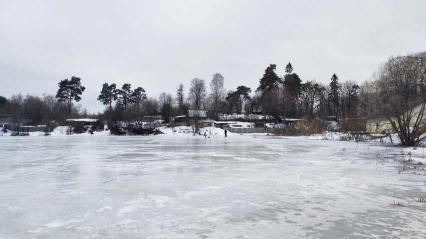 Замерзший пруд и прибрежные домики в зимний день