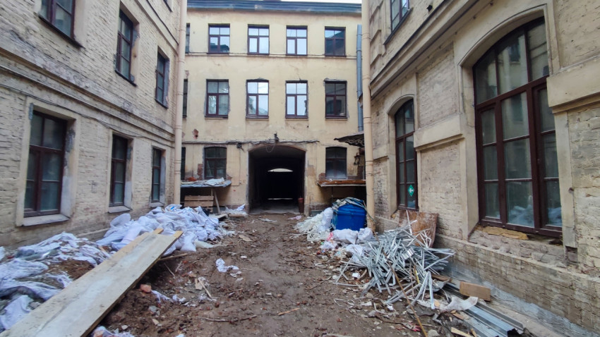 Двор старинного здания с арочным проездом и строительным мусором