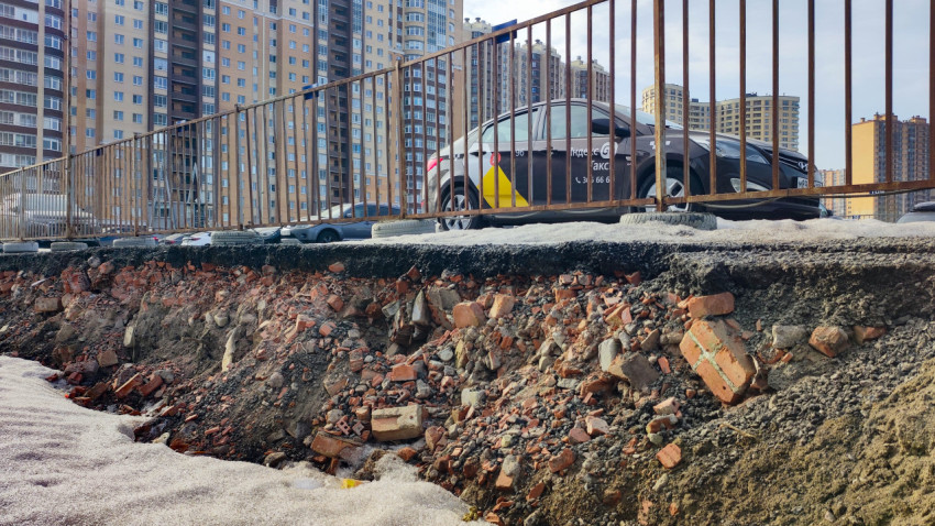 Разрушенный слой асфальта и кирпичный грунт у парковки