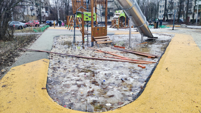 Детская площадка во дворе с ледяными лужами после оттепели