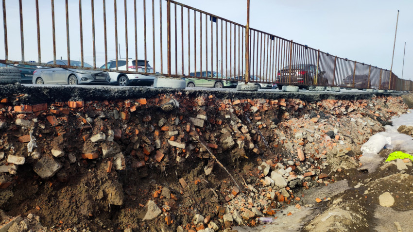 Обрушенный край парковки с ограждением и слоями кирпичного грунта