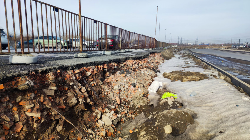 Разрушенный край парковочной площадки с металлическим забором