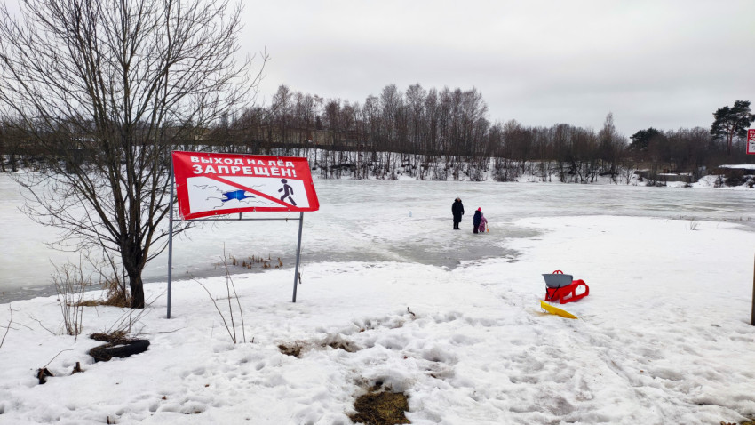 Предупреждающий знак у замерзшего пруда зимой