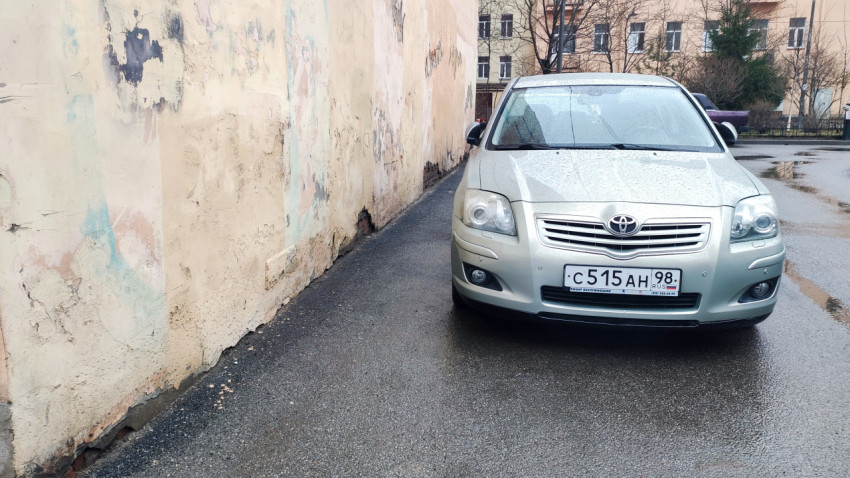 Серебристый автомобиль у стены старого дома