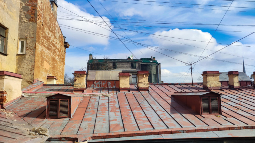 Металлическая кровля старого жилого дома с вентиляционными шахтами