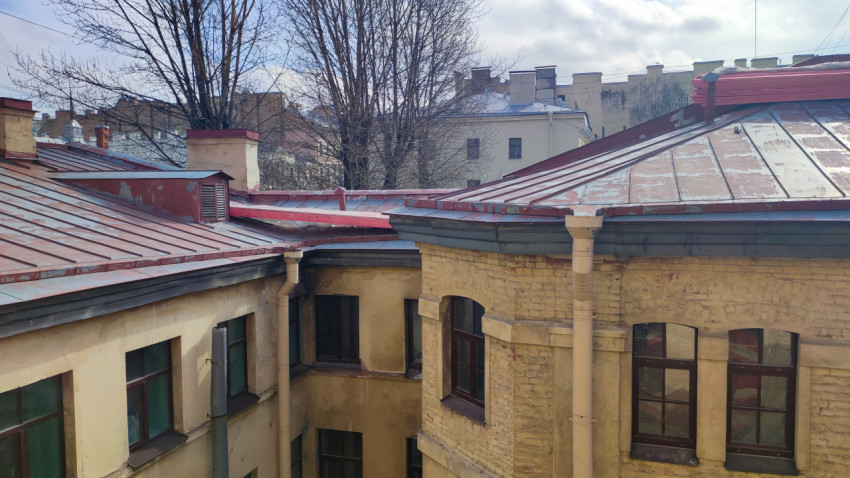 Двор старого кирпичного дома с металлической кровлей