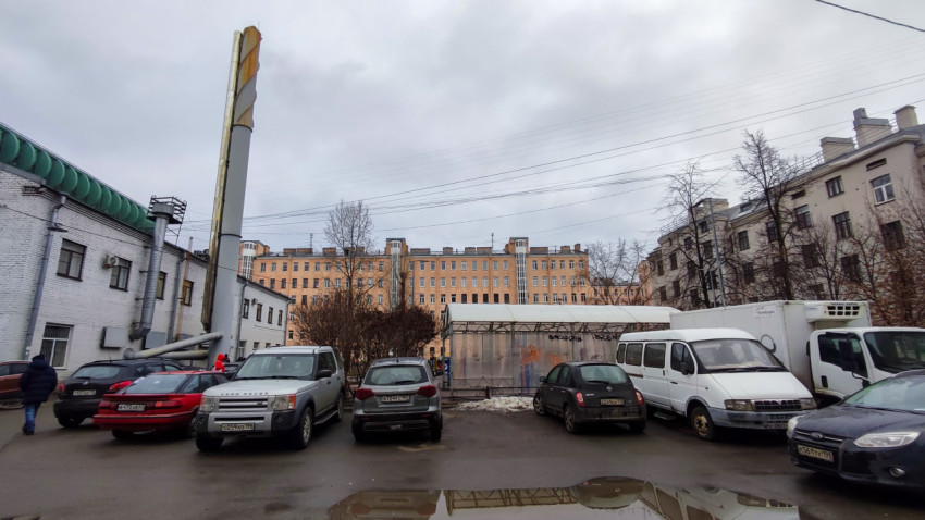 Автомобили и дымовая труба у производственного здания