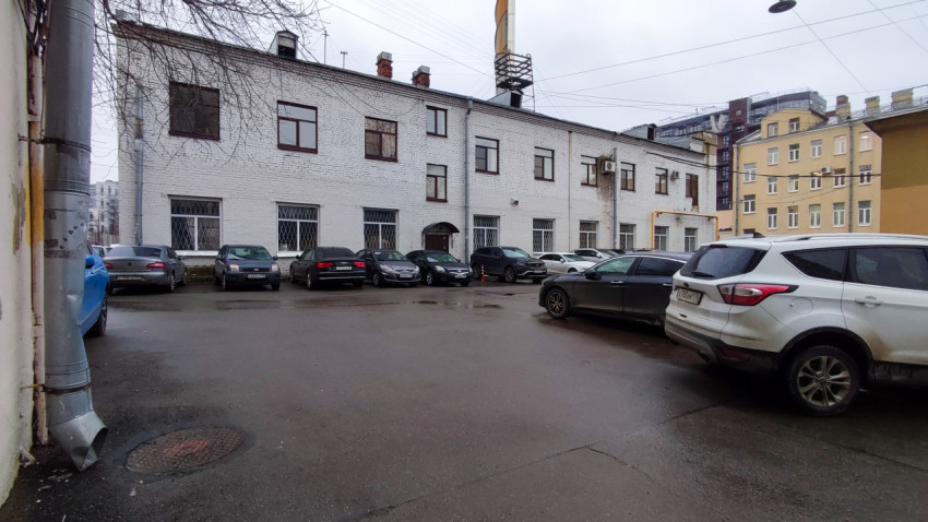 Асфальтированный двор с припаркованными автомобилями у белого здания