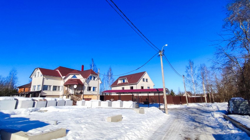 Загородные жилые дома у зимней улицы с линиями электропередачи