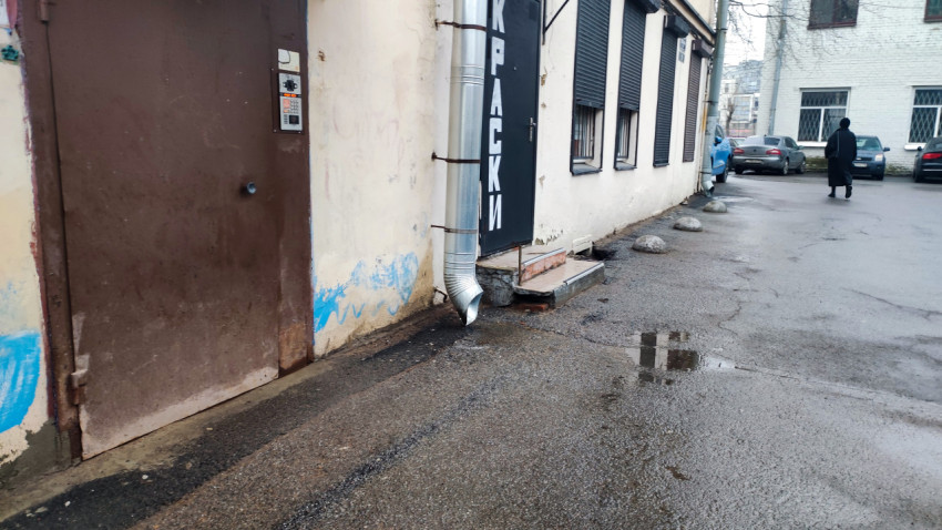 Старая дверь и водосточная труба на фасаде здания