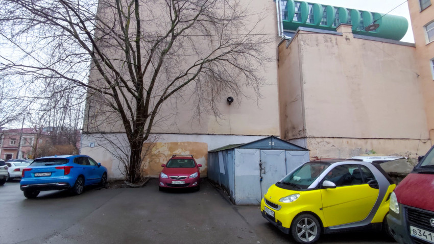 Парковка у стены жилого дома с металлическим гаражом