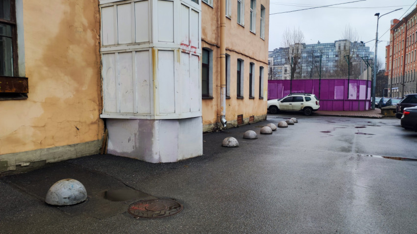 Ряд бетонных ограничителей у старого жилого дома