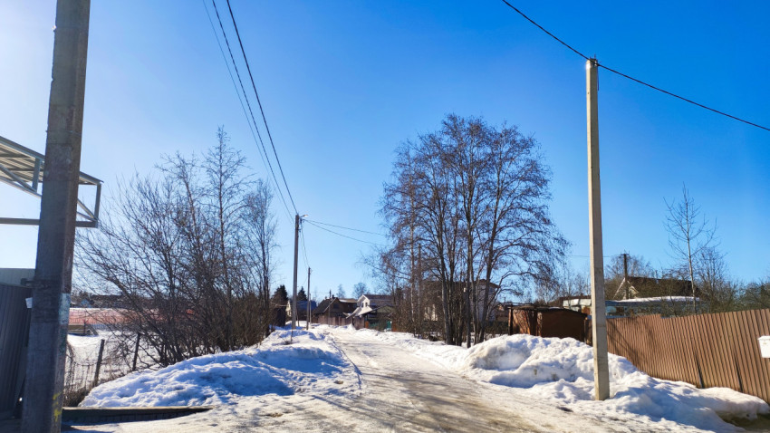 Сельская дорога с ограждением и электросетями в зимний период