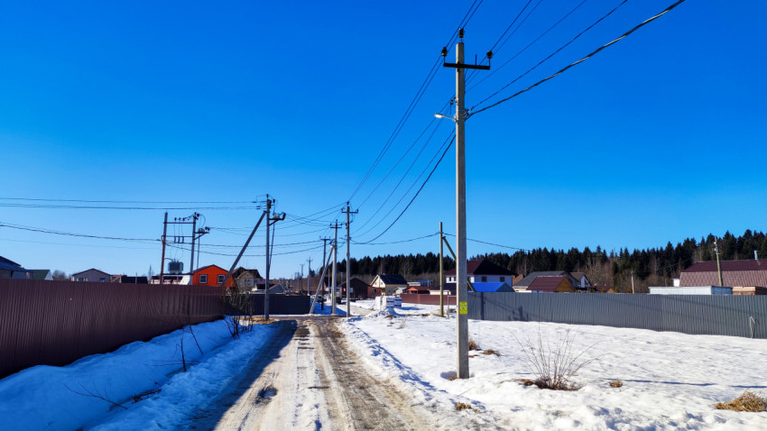 Сельская улица с опорами ЛЭП и частной застройкой
