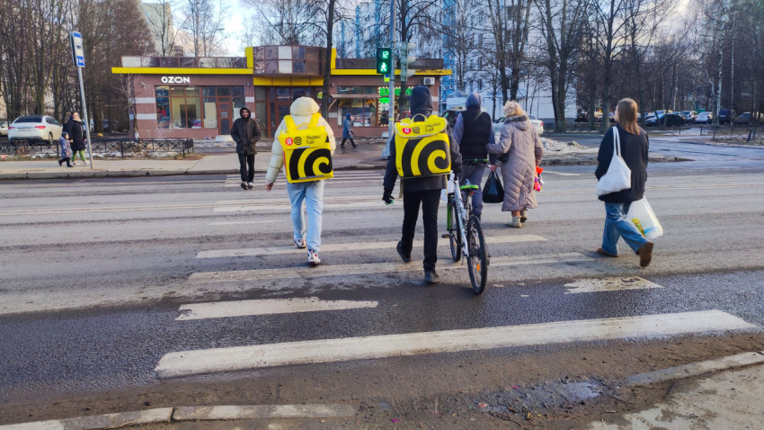 Курьеры сервиса доставки Яндекс Еда переходят дорогу на пешеходном переходе