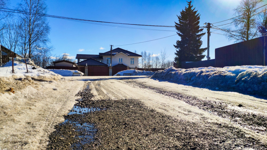 Загородная улица с жилыми домами и талым снегом
