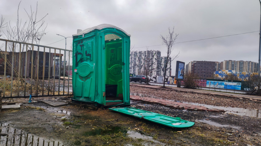 Зеленый уличный туалет на фоне жилых комплексов