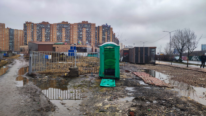 Разбитая уличная туалетная кабина на фоне жилых домов