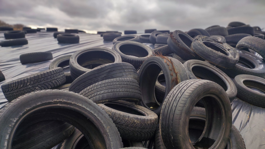 Груды старых автомобильных шин на силосной плёнке
