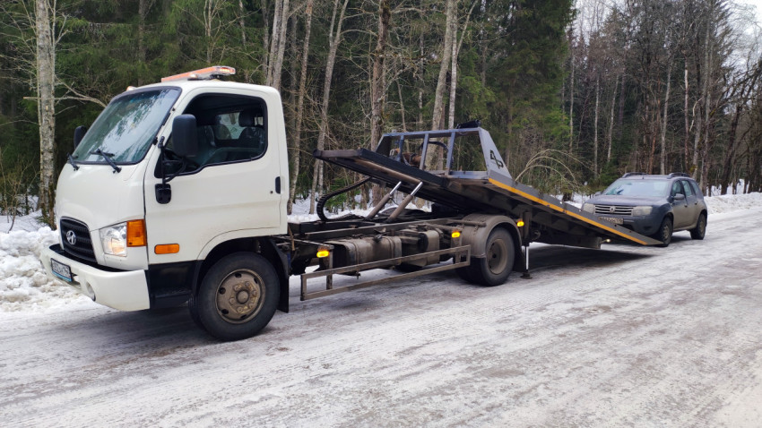 Эвакуатор с выдвинутой платформой на зимней трассе