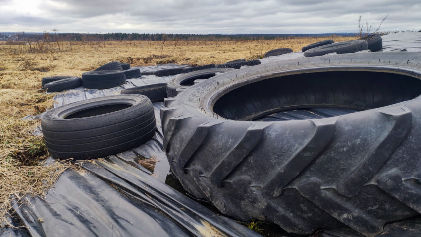 Автомобильные шины и тракторное колесо на фермерском силосе