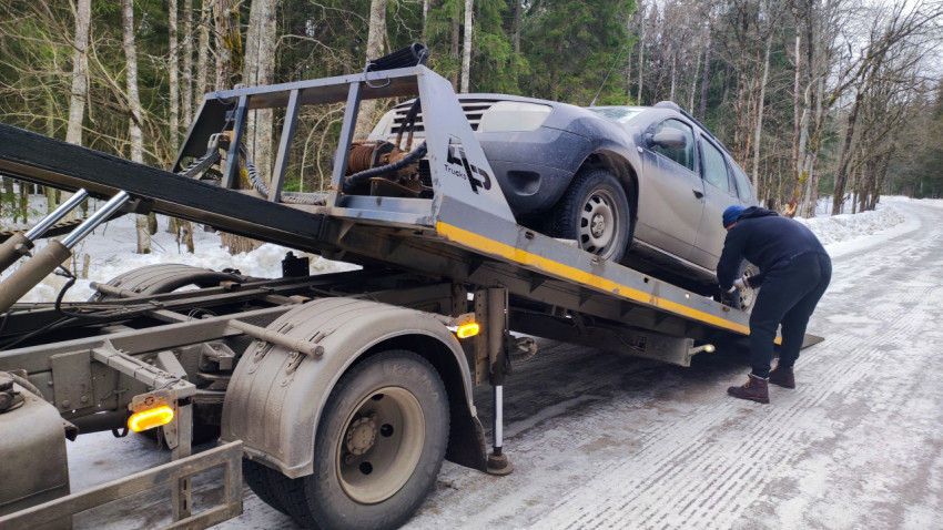 Работник крепит автомобиль Renault Duster на платформе эвакуатора