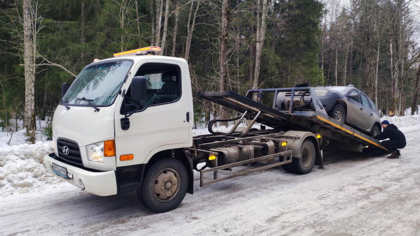 Автомобиль Renault Duster загружается на эвакуатор Hyundai в зимнем лесу