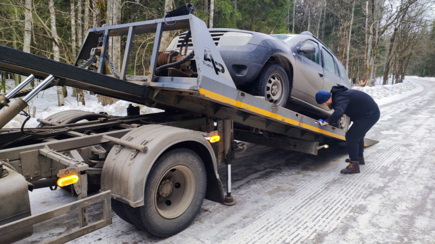 Работник проверяет крепление эвакуируемого автомобиля Renault Duster