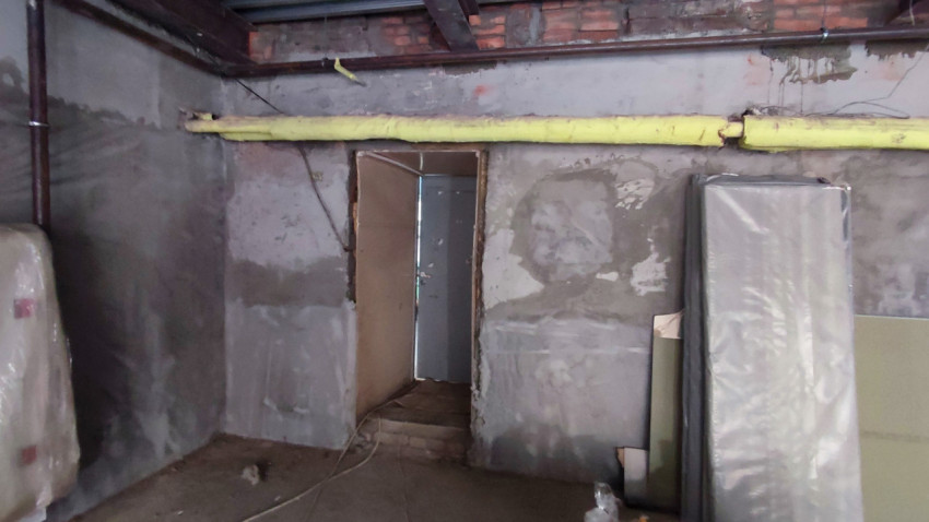 Ремонтная комната с оштукатуренными стенами и металлическими коммуникациями