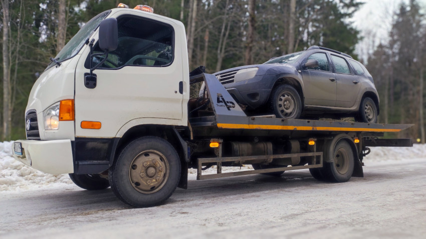 Работник эвакуаторной службы завершает погрузку автомобиля Renault Duster