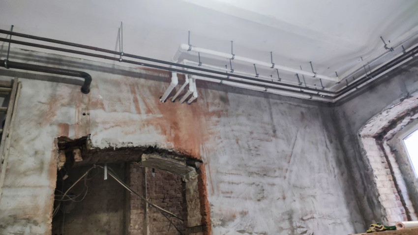 Система трубопроводов и фрагмент стены старого здания при ремонте